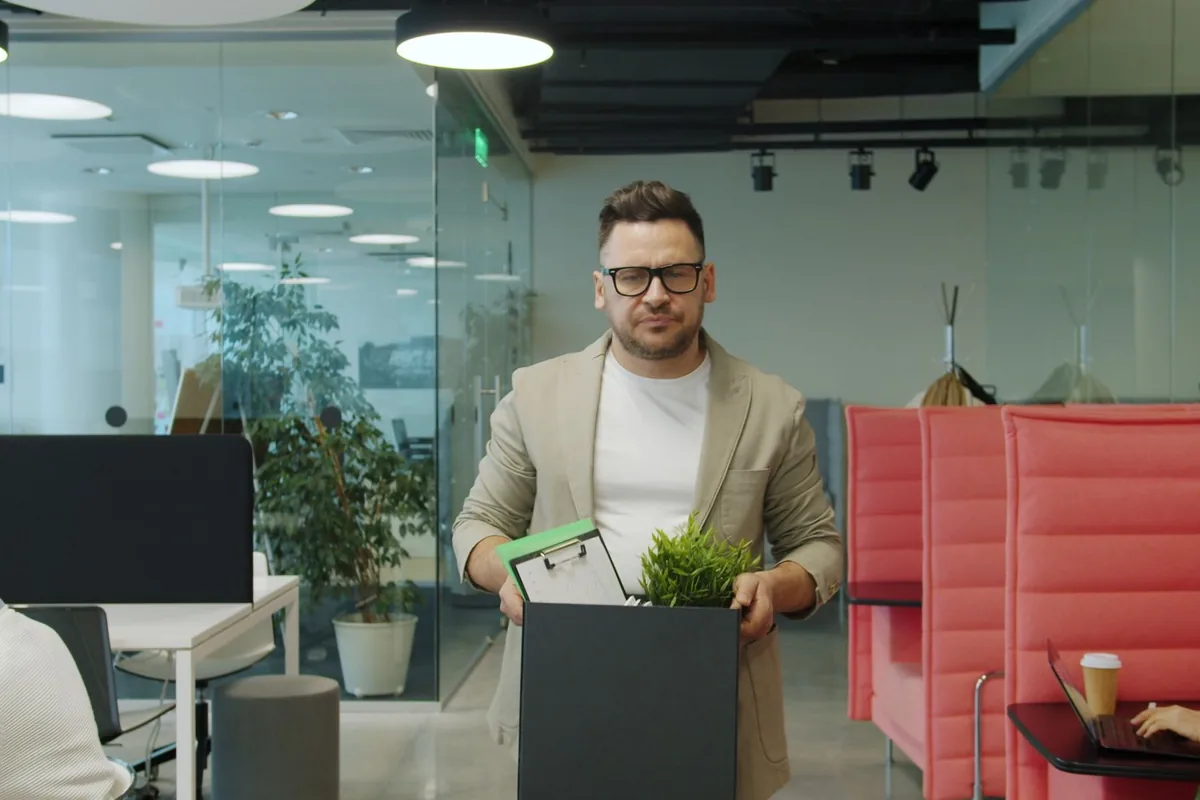 Ein Mitarbeiter trägt eine Pflanze durch ein geräumtes Büro