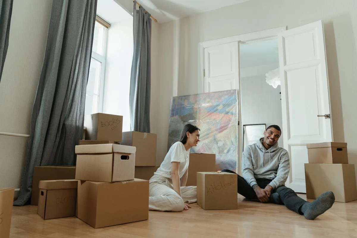 Zwei Personen prüfen Unterlagen zwischen gepackten Kartons
