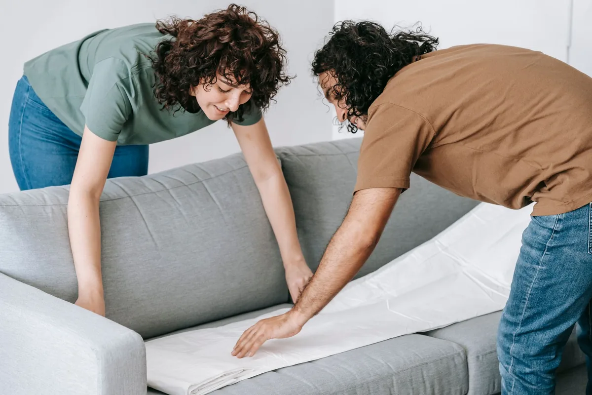 Zwei Personen verpacken ein Sofa für den Transport