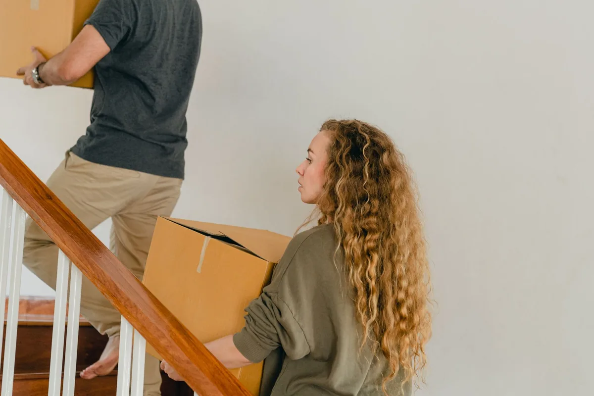 Zwei Personen reichen sich Kartons auf einer Innentreppe