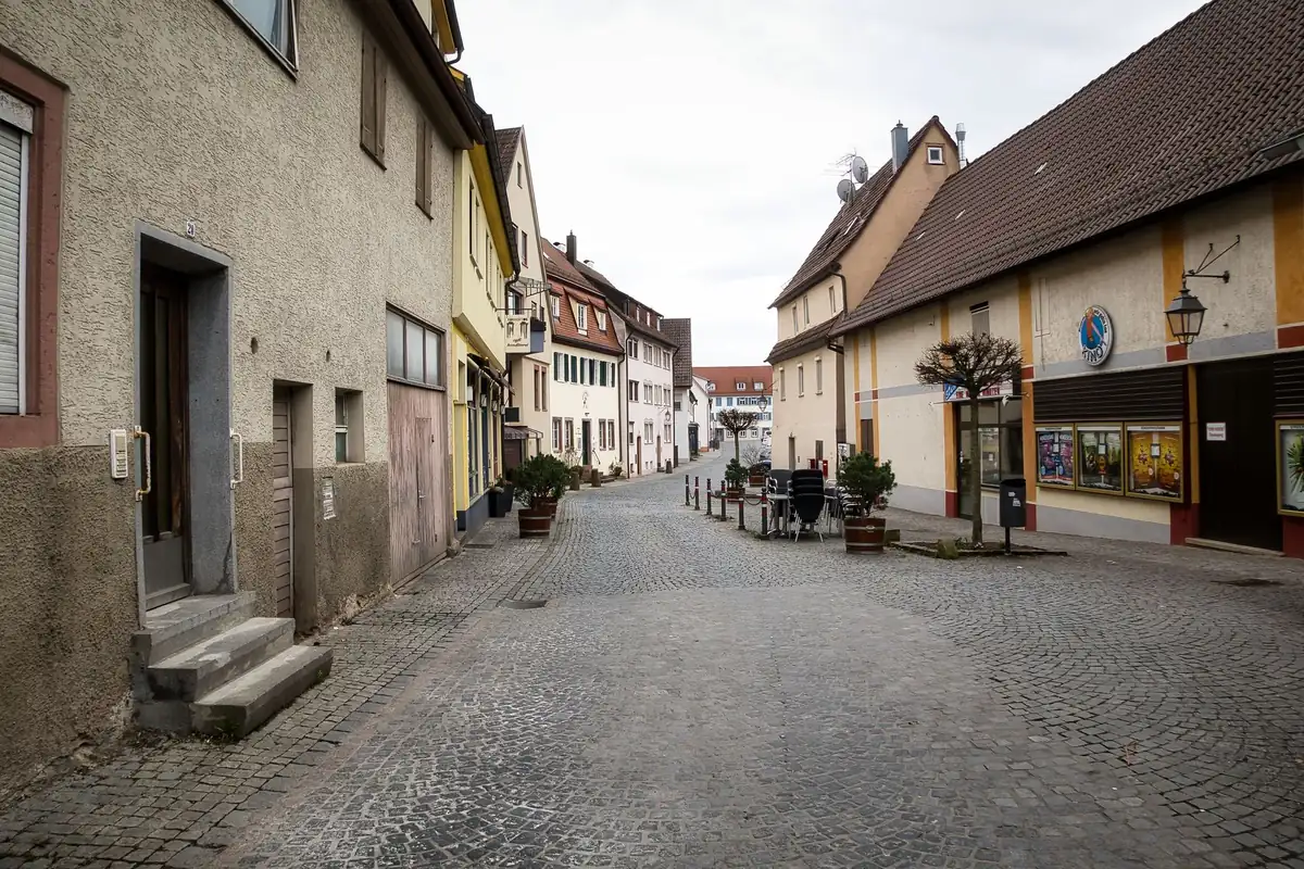 Eine gepflasterte Straße verläuft durch einen ruhigen Ortskern