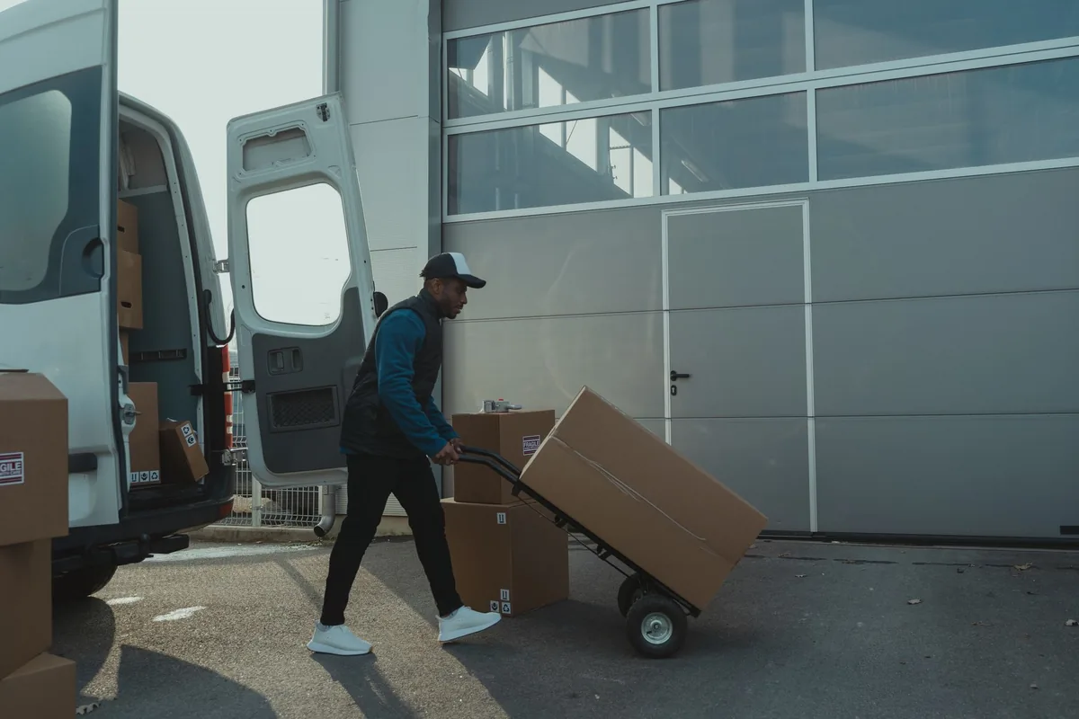 Ein Helfer lädt Kartons in einen geöffneten Transporter